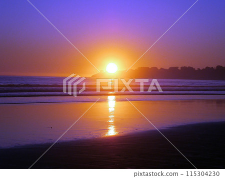 Epic sunset reflects on ocean and beach on an empty clear sky day 115304230