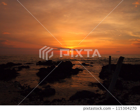 Sunset over ocean with lava rocks of Holoholokai Beach in the foreground 115304270