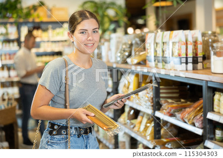 Girl choosing pasta in natural grocery section of supermarket 115304303