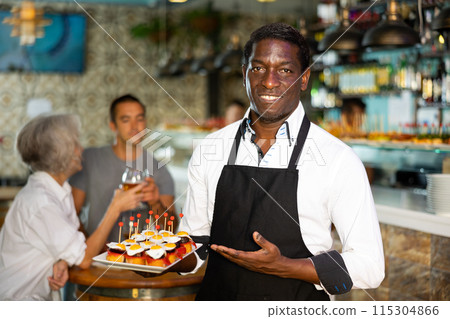 Professional african american waiter holding serving tray for restaurant guests Professional african american waiter holding serving tray for restaurant guests 115304866