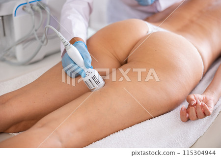 Hardware anti-cellulite procedure on thighs of young woman in beauty clinic Hardware anti-cellulite procedure on thighs of young woman in beauty clinic 115304944