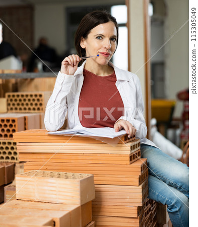 Interested brunette making notes while planning home renovation 115305049