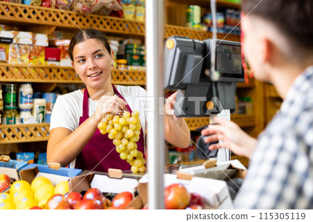 Female shopping assistant weighing grapes in grocery shop 115305119