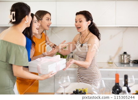 Happy woman receiving gift from besties at birthday bash 115305244