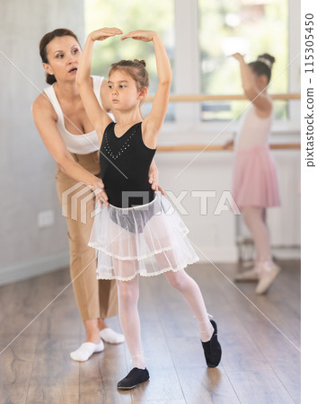 Woman teacher corrects movement of girl dancer 115305450