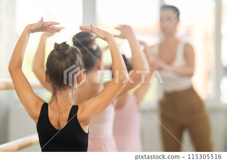 Girls in ballet class perform fifth position with correction of female mentor Girls in ballet class perform fifth position with correction of female mentor 115305516
