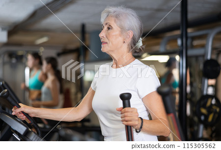 Elderly woman training on an elliptical machine 115305562