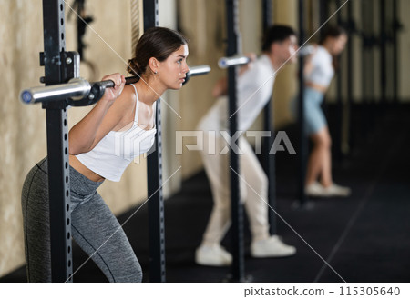 Young woman training with barbell in gym Young woman training with barbell in gym 115305640