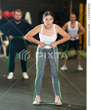 Determined young girl working out with resistance band in gym 115305659
