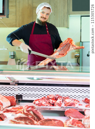 Male butcher cuts pieces from a sheep carcass with knife Male butcher cuts pieces from a sheep carcass with knife 115305726