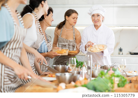 Mature female cook holding cutting board with raw chicken 115305779