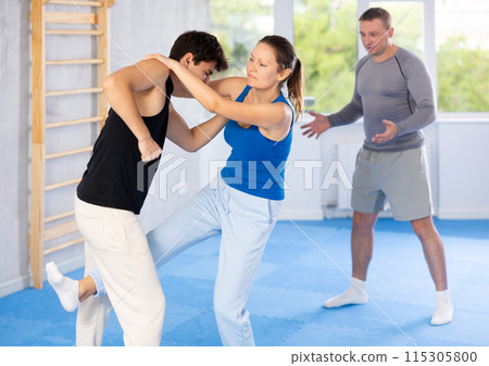 Woman practices blows to head of her attacking man during self-defense training under the guidance of trainer Woman practices blows to head of her attacking man during self-defense training under the guidance of trainer 115305800