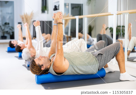 Group of different people doing exercises with roller 115305837