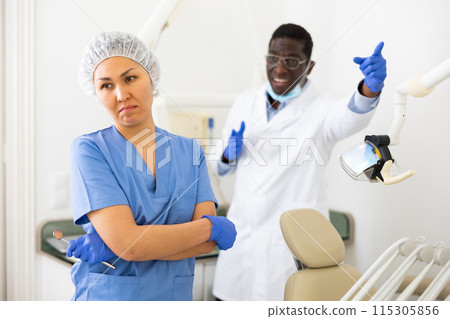 Doctor dentist is dissatisfied with the work of nurse 115305856