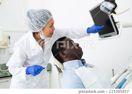 Doctor dentist shows the patient the result of dental x-ray 115305857