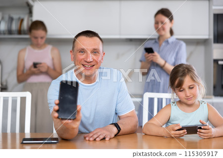 Father showing the screen of her phone. Children and husband typing on smartphone screen 115305917