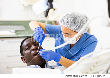 Dentist examining oral cavity of man in dental clinic 115305948