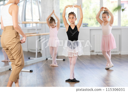 Little girls are learning various dance and ballet movements in studio Little girls are learning various dance and ballet movements in studio 115306031