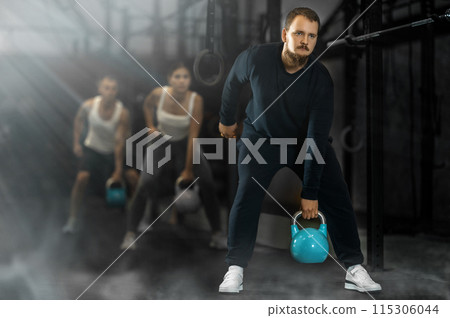 Sportive young man lifting heavy kettlebell in sports hall Sportive young man lifting heavy kettlebell in sports hall 115306044