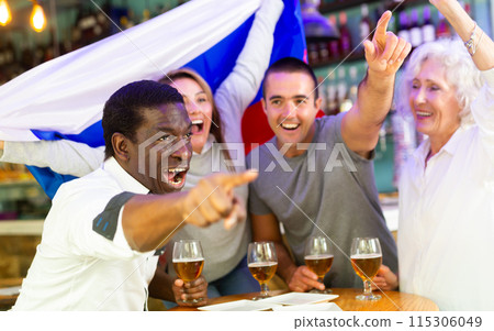 Cheerful diverse soccer supporters with flag of Russia spending time together with pint of beer in the pub Cheerful diverse soccer supporters with flag of Russia spending time together with pint of beer in the pub 115306049