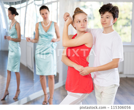 Motivated adolescent ballroom dancers practicing dance moves in studio Motivated adolescent ballroom dancers practicing dance moves in studio 115306056