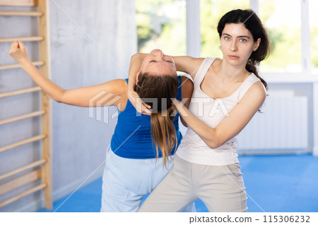 Two women training self-defense techniques in studio 115306232