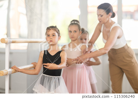 Woman teacher corrects girls in batman tandu movement Woman teacher corrects girls in batman tandu movement 115306240