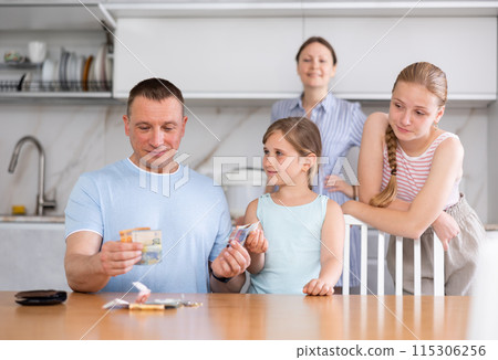 Joyful daughters surrounded dad in kitchen and asked for money Joyful daughters surrounded dad in kitchen and asked for money 115306256