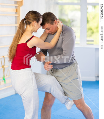 Young girl practicing feet kick method of self-defense in pair with middle-aged man Young girl practicing feet kick method of self-defense in pair with middle-aged man 115306293