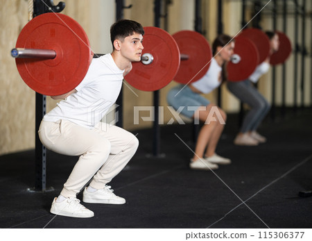 Young guy training with barbell in gym Young guy training with barbell in gym 115306377