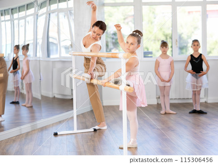 Little ballerinas together with choreography teacher in grand batman pose learn to dance ballet Little ballerinas together with choreography teacher in grand batman pose learn to dance ballet 115306456