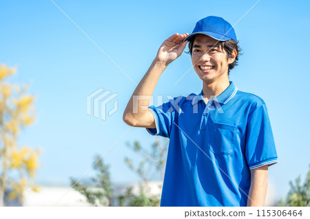 A young male driver in work clothes wearing a hat 115306464
