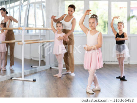Girls in ballet class perform forth position with correction of female mentor 115306488