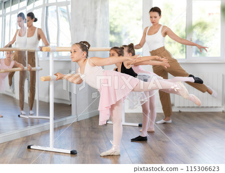Woman teacher corrects girls in arabesque movement Woman teacher corrects girls in arabesque movement 115306623