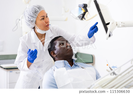 Doctor dentist shows the patient the result of dental x-ray Doctor dentist shows the patient the result of dental x-ray 115306630