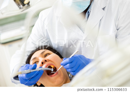 Dentist examining oral cavity of woman in dental clinic Dentist examining oral cavity of woman in dental clinic 115306633