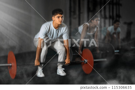 Young guy doing exercises with a barbell in gym Young guy doing exercises with a barbell in gym 115306635