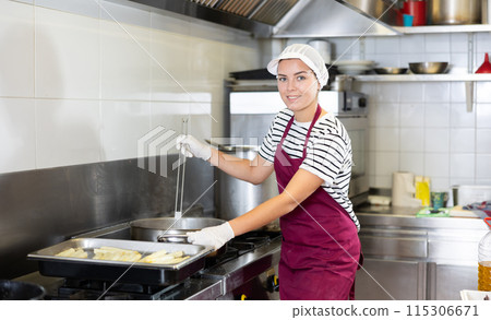 Workwoman preparing food for sale in deli section of store Workwoman preparing food for sale in deli section of store 115306671