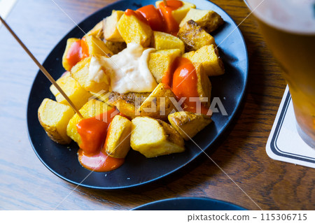 Traditional Spanish fried potatoes Patatas bravas served with cheese sauce and spicy sauce with paprika and chili Traditional Spanish fried potatoes Patatas bravas served with cheese sauce and spicy sauce with paprika and chili 115306715