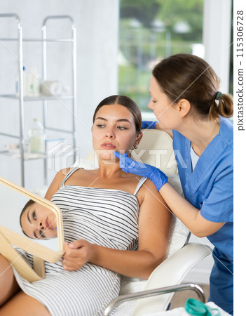 Woman cosmetologist examines patients nasolabial area after lifting procedure and palpates lips mouth 115306728