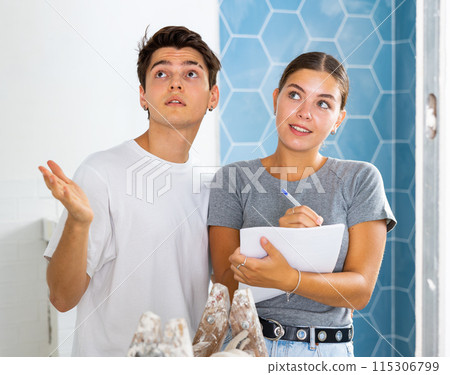 Young couple making notes while working on renovation of house Young couple making notes while working on renovation of house 115306799
