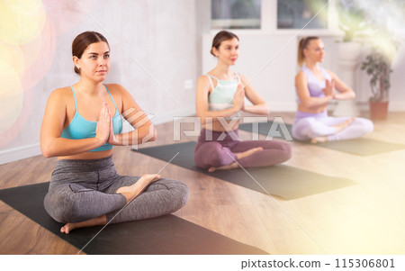 Young girl sitting in Padmasana yoga position with arms in namaste 115306801