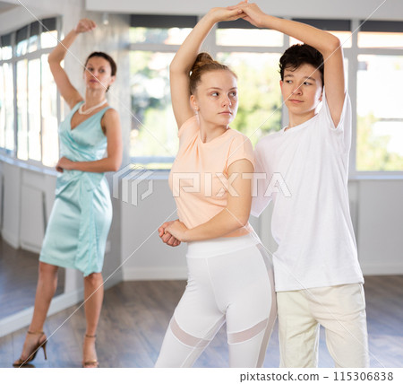 Teenage girl and boy practicing waltz in dance hall with female mentor 115306838