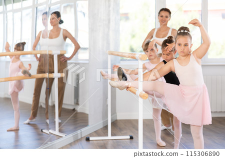 Ballet pose grand batman - little girls at a choreography lesson are learning ballet movements in studio 115306890