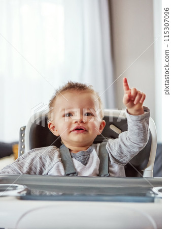 Baby, high chair and house in portrait for development or wellness, motor skills with finger for growth. Young, boy child and hand in home for healthy learning, waiting for meal time in apartment Baby, high chair and house in portrait for development or wellness, motor skills with finger for growth. Young, boy child and hand in home for healthy learning, waiting for meal time in apartment 115307096