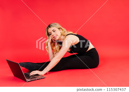 Happy young female do exercises before laptop screen at home or in gymnastic studio. 115307437