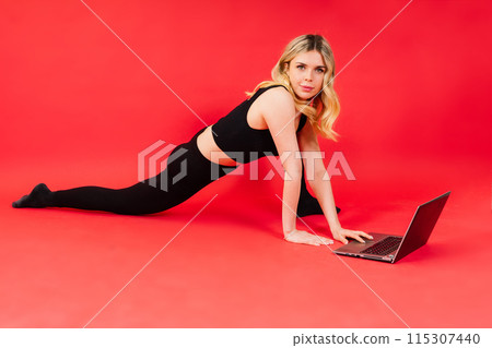 Happy young female do exercises before laptop screen at home or in gymnastic studio. 115307440