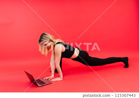 Happy young female do exercises before laptop screen at home or in gymnastic studio. 115307443