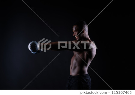 Young man with dumbbells good physique isolated on red and black background. Strength and motivation 115307465