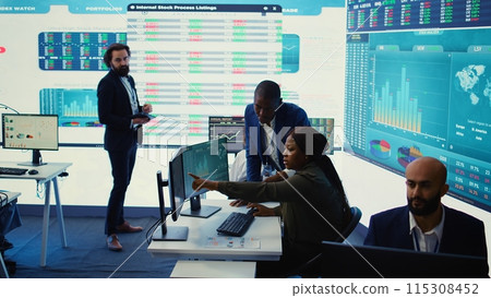Business associates evaluating key performance indicators within the company, conducting evaluations and discussing workflow situation. Workers enhancing productivity and efficiency. Camera B. Business associates evaluating key performance indicators within the company, conducting evaluations and discussing workflow situation. Workers enhancing productivity and efficiency. Camera B. 115308452